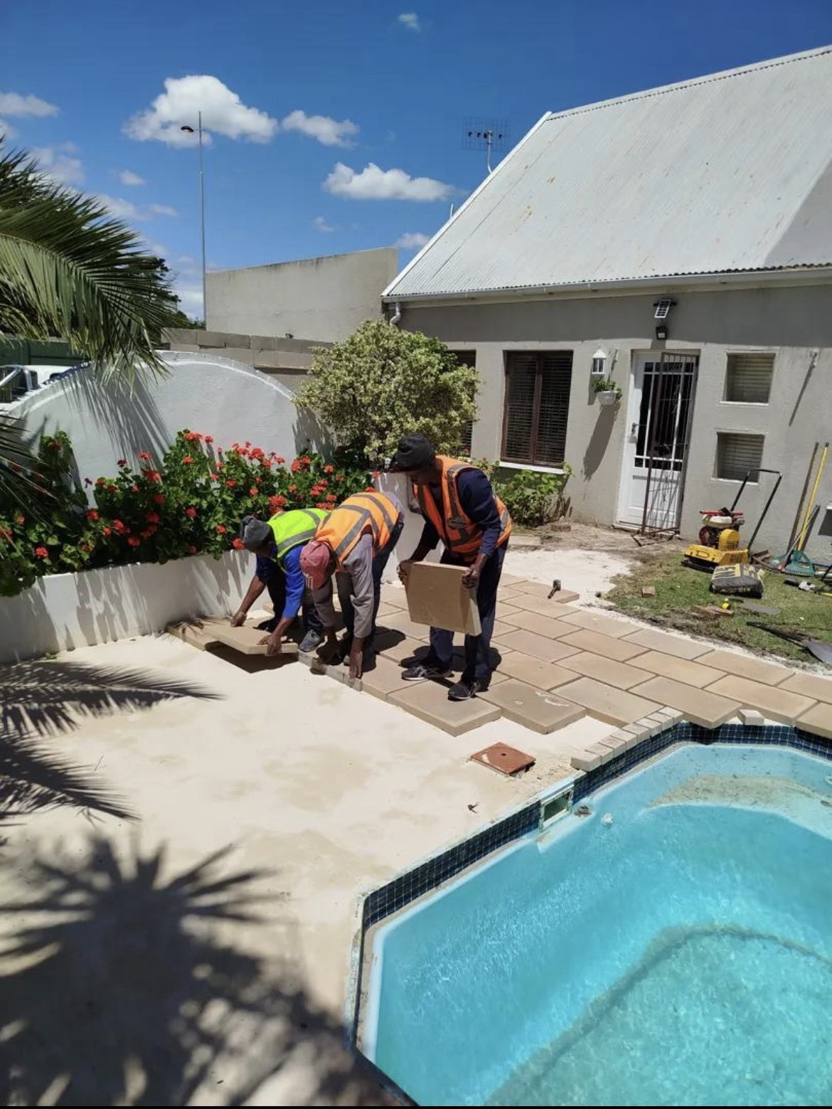 Team laying patio tiling beside a pool